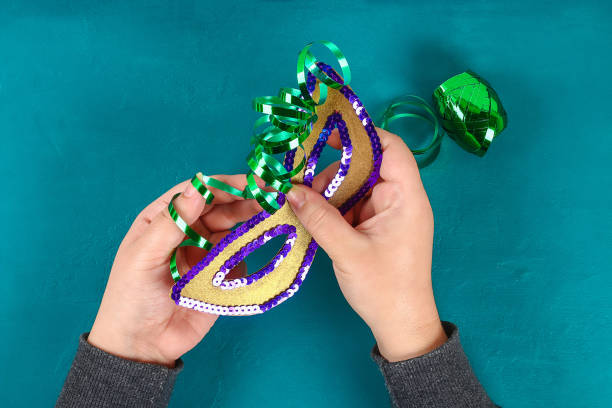 Diy Masquerade mask Mardi Gras, Fat Tuesday. Gift idea, decor Mardi Gras. Carnival mask cardboard, sequins, paper, beads. Step by step. process childrens crafts. Top view. Green yellow purple