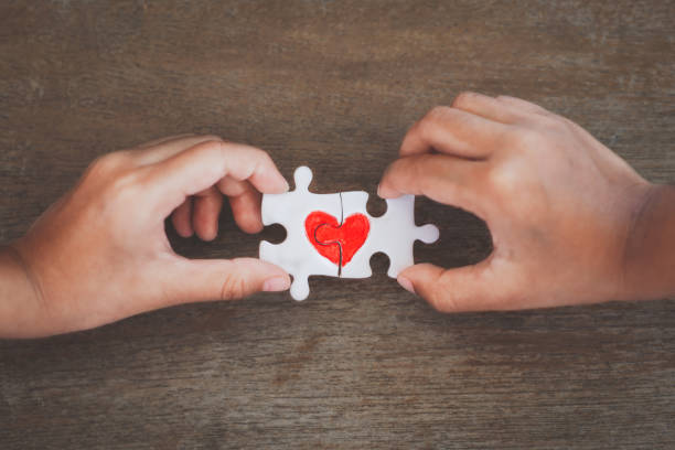 istock Two kid hands connecting couple jigsaw puzzle piece with drawn red heart 1127225732