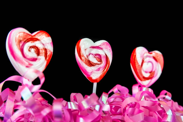 Three Heart Shaped Lollipops On A Black Background stock photo