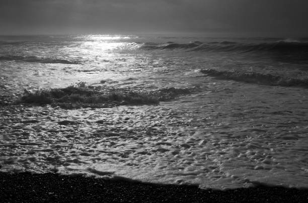 Bright sun reflects off of white foam on beach as waves break, China Beach, Vancouver Island, British Columbia.