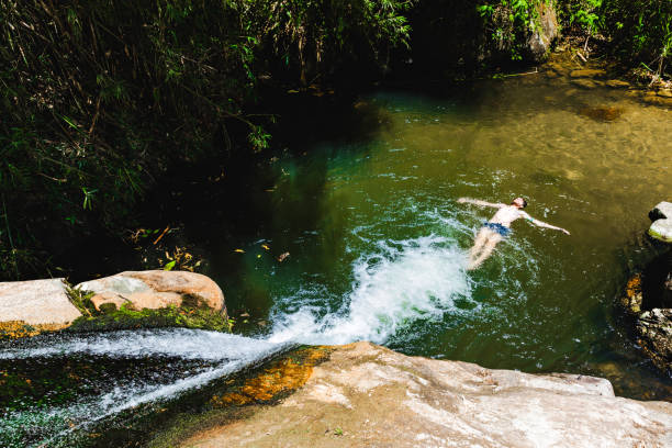 Young man floating on natural pool by a waterfall at Lumiar/RJ