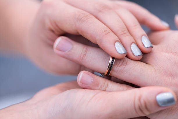 istock Wedding theme, Bride putting ring on groom hand, and they holding hands with a nice manicure neat. 1127242236