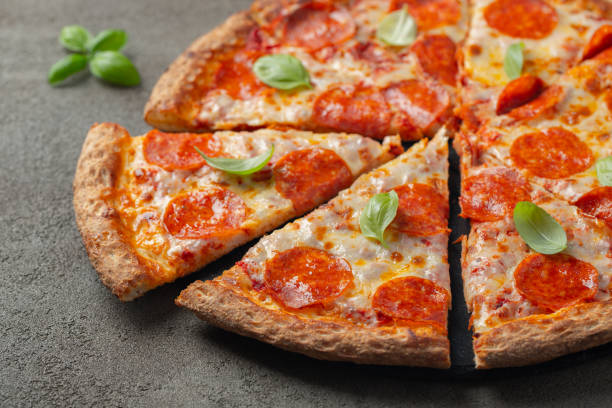 istock Tasty pepperoni pizza with basil on brown concrete background 1127243516
