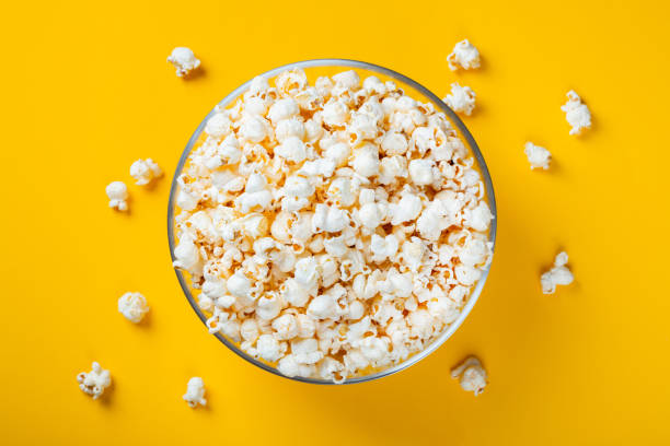 istock Glass bowl with salted popcorn on yellow background. Top view with copy space. Flat lay 1127243529