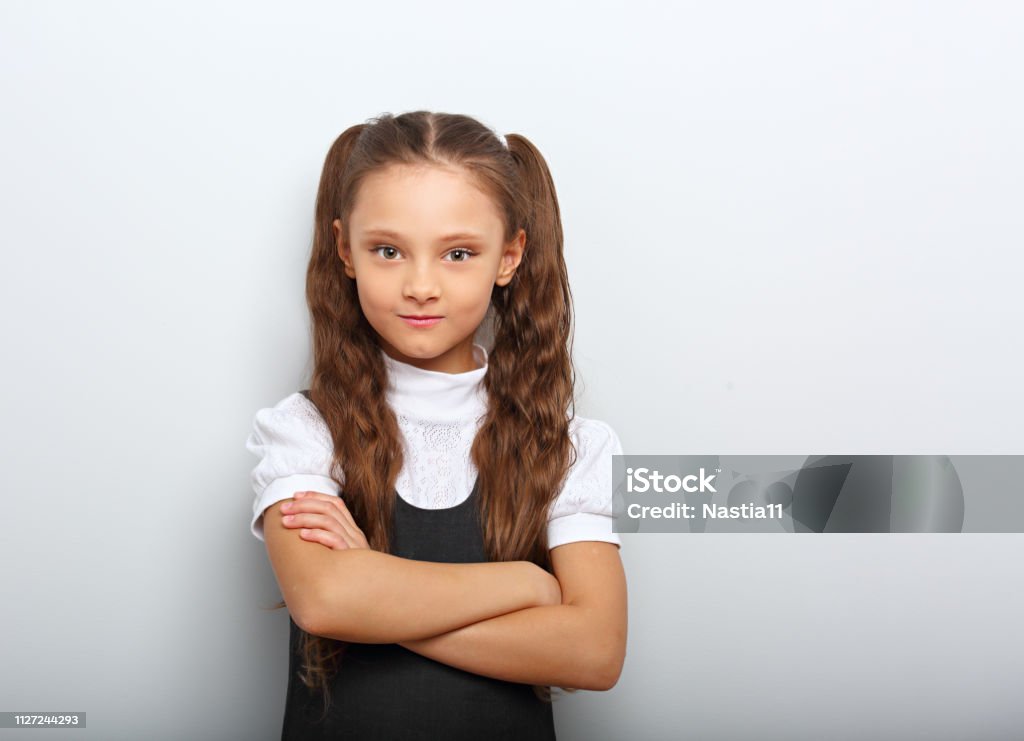 Fun Pupil School Girl With Long Hair Style In Uniform Looking Serious With  Folded Arms On Blue Background With Empty Copy Space Stock Photo - Download  Image Now - iStock