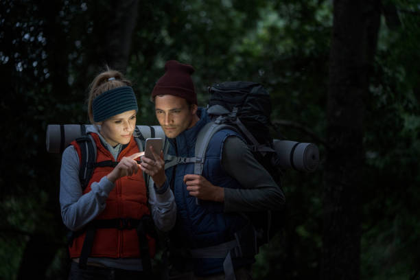 istock Young hiking couple using smart phone in forest 1127245330