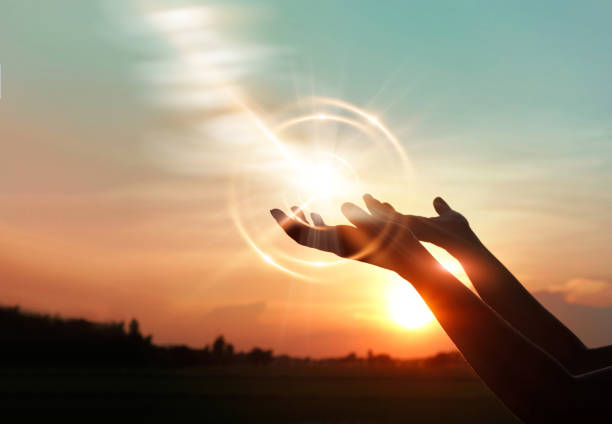 manos de mujer pidiendo la bendición de dios sobre fondo puesta de sol - gods rays fotografías e imágenes de stock