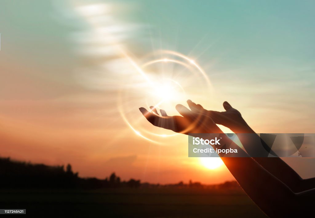 Woman hands praying for blessing from god on sunset background Spirituality Stock Photo