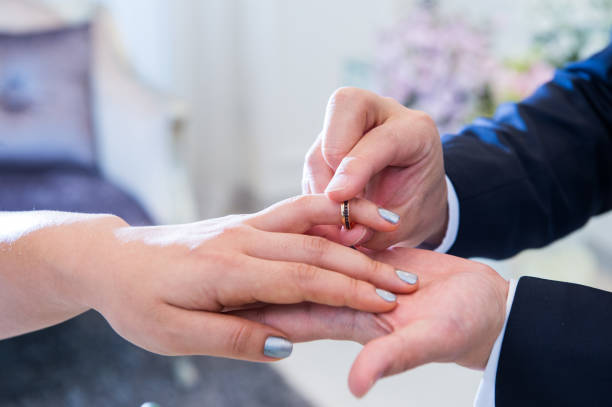 istock Wedding theme, Bride putting ring on groom hand, and they holding hands with a nice manicure neat. 1127245555