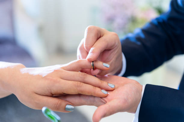 istock Wedding theme, Bride putting ring on groom hand, and they holding hands with a nice manicure neat. 1127245590