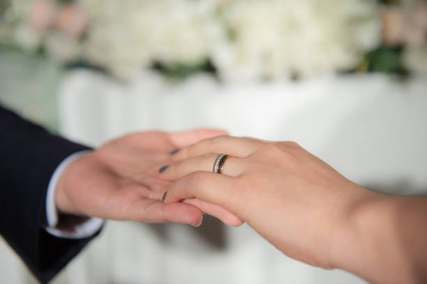 istock Wedding theme, Bride putting ring on groom hand, and they holding hands with a nice manicure neat. 1127245643