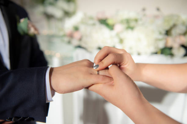 istock Wedding theme, Bride putting ring on groom hand, and they holding hands with a nice manicure neat. 1127245668