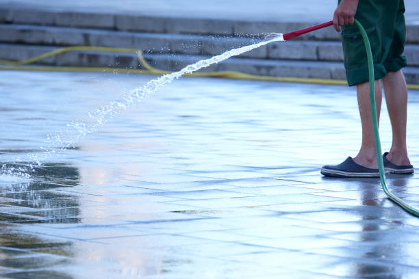 istock worker from a hose watering the city street 1127246626