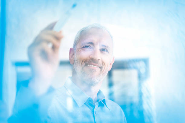 istock Confident businessman writing on glass wall 1127246762