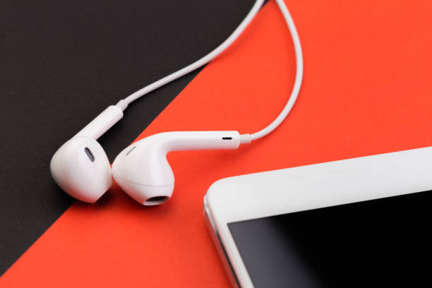 istock white earphones with phone on black  and red background 1127247229