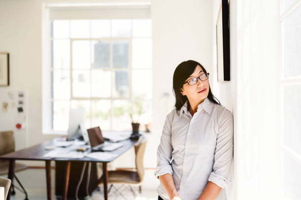 istock Businesswoman looking away while leaning on wall 1127247816