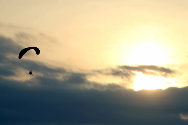 istock Paraglider flying on a wing in the sky against the setting sun 1127248976