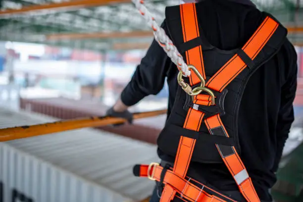 Photo of Construction worker wearing safety harness and safety line working on construction.