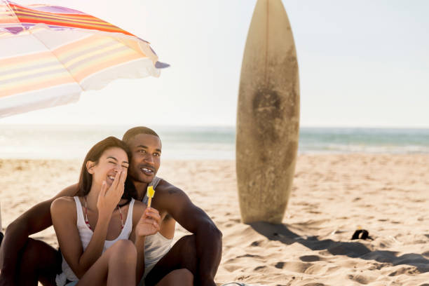istock Cheerful woman sitting with man at beach 1127250285