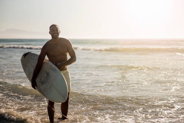 istock Happy shirtless man carrying surfboard at beach 1127250555