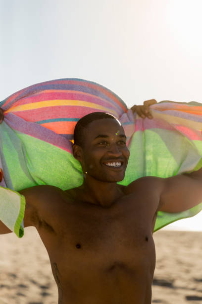 istock Happy shirtless man holding towel at beach 1127250592