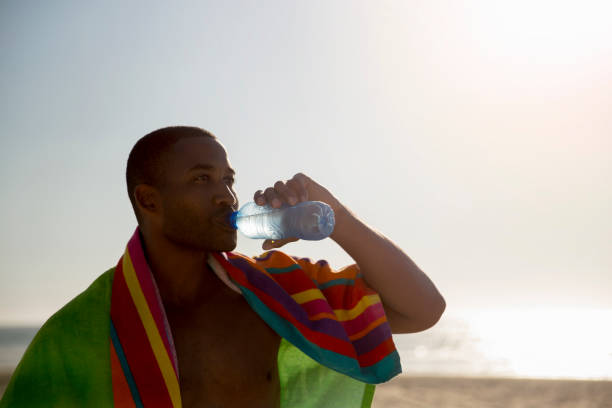 istock Thoughtful man drinking from water bottle at beach 1127250597