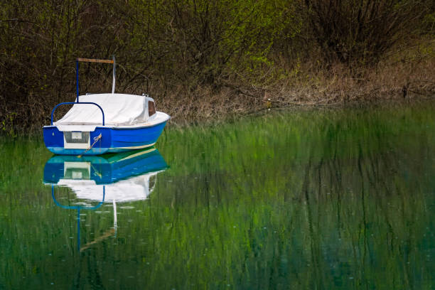 Small empty white and blue fisherman boat on the shore of lake Skadar in Virpazar, Montenegro