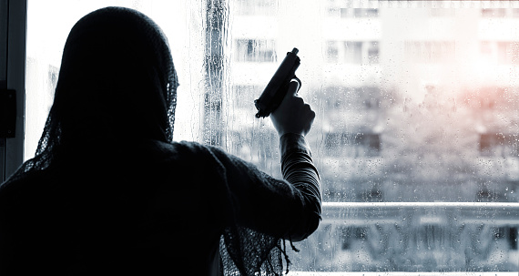 Terrorist criminal with gun in hand on building, rain drop background. Black and white.