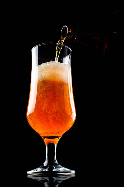 istock Beer is pouring into a glass from bottle on black background 1127254316