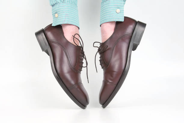 istock Classic brown shoes worn on the hands on a white background 1127254560