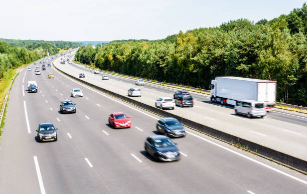 Heavy but fluid traffic on the A10 highway in France by a sunny day. Heavy but fluid traffic on the eight-lane A10 highway in France in the direction of Paris by a hot summer day with cars, vans, trailers and semitrailer truck driving. essonne stock pictures, royalty-free photos & images