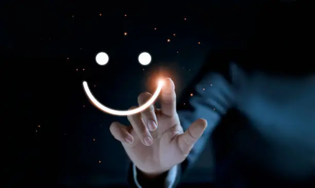 Photo of Finger of businessman touching and drawing face emoticon smile on dark background, service mind, service rating. Satisfaction and  customer service concept.