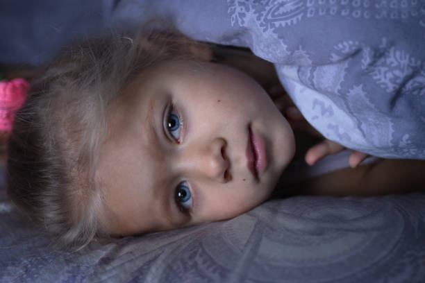 istock The little girl is sick and basks under the covers in bed 1127258538