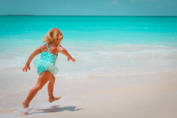 istock little girl run play with waves on the beach 1127259556