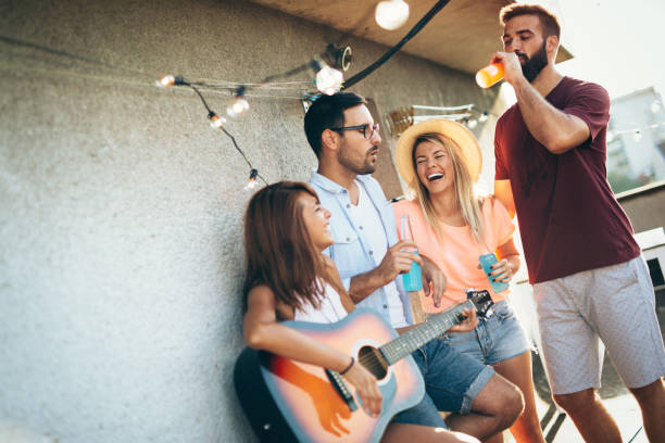 istock Group of happy friends having party on rooftop 1127264526