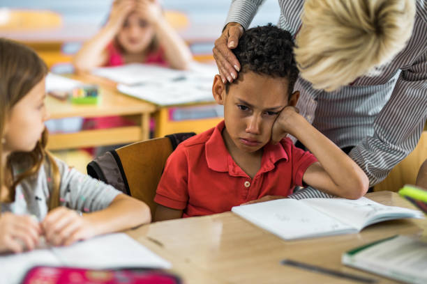 istock Female teacher consoling crying black student in the classroom. 1127266168