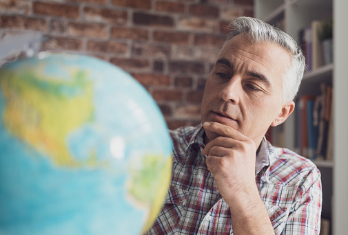 Man holding a globe and searching locations, he is planning his vacations and an international travel