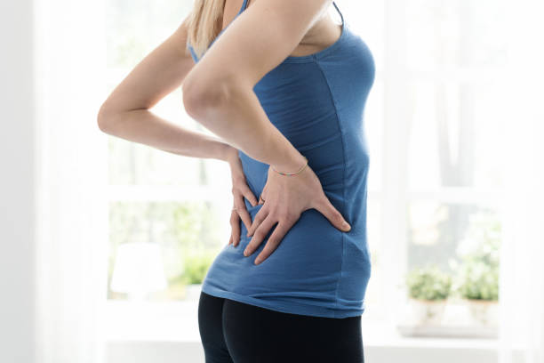giovane donna sportiva che si tocca la parte bassa della schiena, sente dolore - back rear view pain backache foto e immagini stock