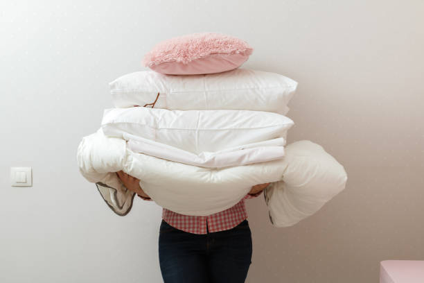istock Woman holding a pile of bedding for sleeping 1127268499
