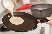 Closeup cooking pancakes on a gas stove. On a hot skillet liquid dough from the ladle is poured