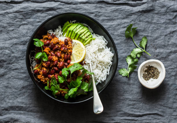 bol de arroz con frijol picante guiso de carne picada con cilantro y aguacate en fondo gris, vista superior - chili food bowl ready to eat fotografías e imágenes de stock