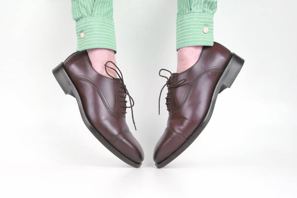 istock Classic brown shoes worn on the hands on a white background 1127272528