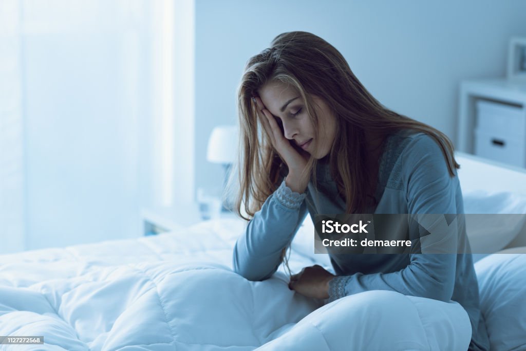Deprimida mujer despierta en la noche, ella está tocando su frente y sufre de insomnio - Foto de stock de Insomnio libre de derechos