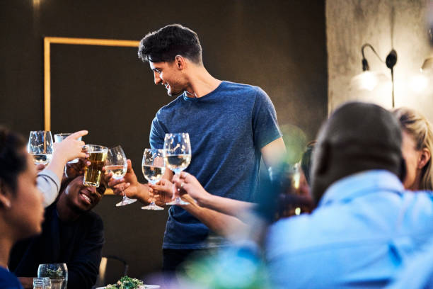 istock Young man toasting glasses with friends in bar 1127274369
