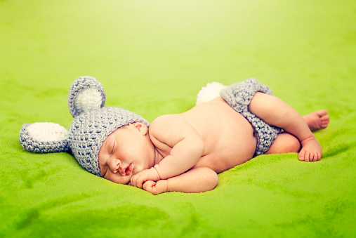 Little bunny. Photo session of a newborn in a rabbit costume. Little bunny on a green blanket. Springtime bunny sleeps on green grass.