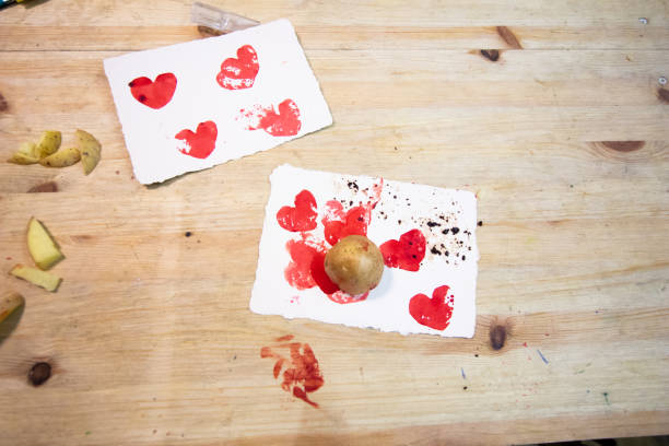 Carving potato. potatoes, colored ink, knives and paper on a wooden table to make stamps with potatoes. stock photo