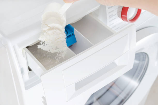 istock washing powder, detergent in a cup and womans hand, washing machine, selective focus 1127277037