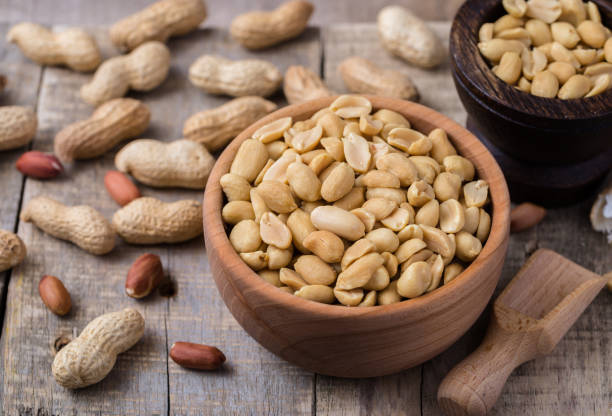 arachides dans un petit bol en bois sur bureau rustique naturel. - peanut photos et images de collection