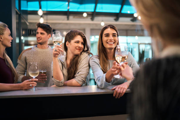 istock Woman receiving wine from bartender by friends 1127278982