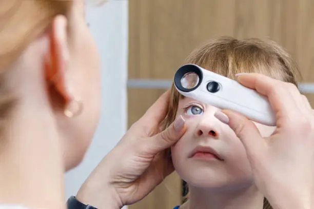 Photo of A closeup of an ophthalmologist checking the eye of a child.